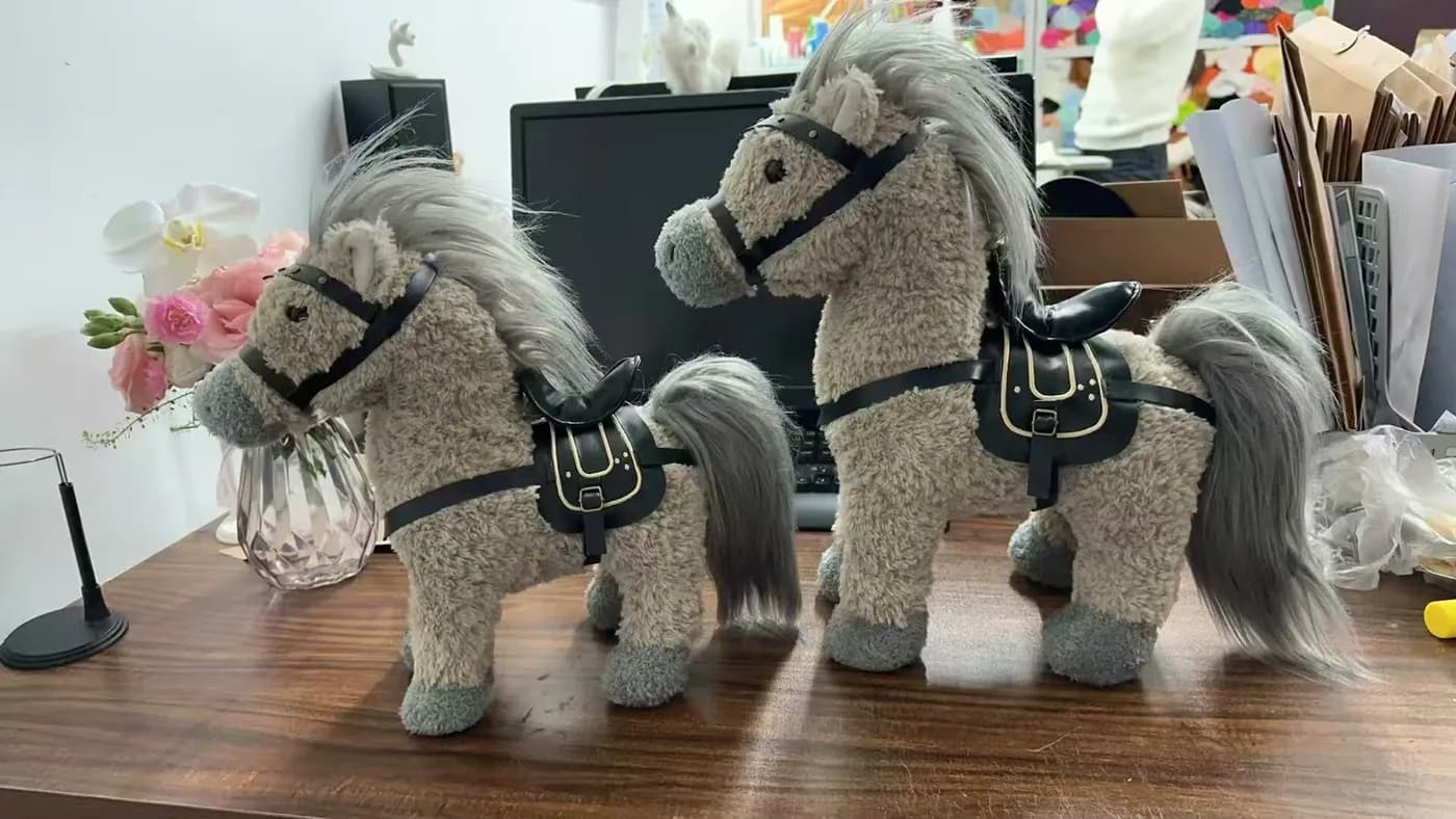 Pair of grey horse plush toys with saddles and bridles